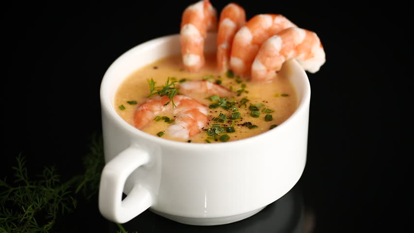 Creamy shrimp soup served in white cup with fresh herb garnish