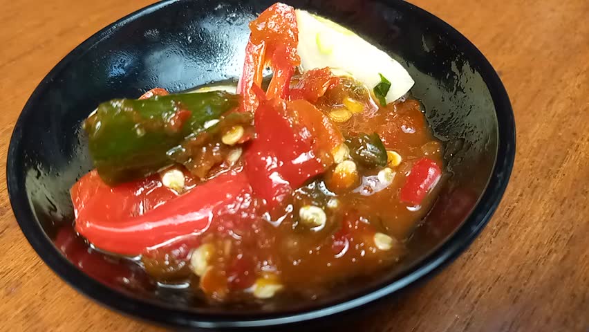 Sambal shows the preparation and presentation of sambal, a traditional Indonesian chili condiment made from fresh chilies, garlic, shallots, and other spices. The footage highlights the vibrant colors, textures, and cooking process of this iconic spicy sauce. This video represents Indonesian cuisine, traditional food preparation, culinary culture, and flavorful condiments.