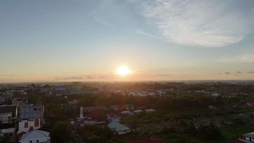 A serene sunset scene over a sprawling city and green suburbs. 