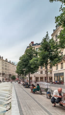 Hyperlapse of Place de la Republique in the historical center of Lyon, France. The square is dominated by a large fountain, surrounded by historic buildings, with people sitting on benches timelapse