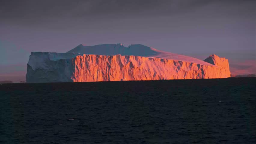 Dawn over Antarctic coast. Polar night sunset. Ocean covered ice. Top above aerial view. Antarctica snow mountain. Sky sunrise Antarctica winter. Open water. Beautiful sky landscape.