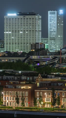 Panoramic aerial timelapse of Katendrecht peninsula at night and Maashaven harbour in Rotterdam, The Netherlands. Illuminated city skyline and traditional Dutch waterfront houses with modern towers