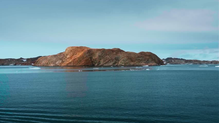 Majestic winter Antarctic aerial landscape. Frozen polar ocean, green rock hill, icebergs, snow covered mountains, seagulls flying in blue sky. Antarctica travel exploration. Explore South Pole nature