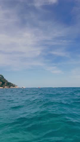 Vertical footage from a SUP board, a man films the sea and surrounding nature with a camera. Water sports concept. High quality 4k footage
