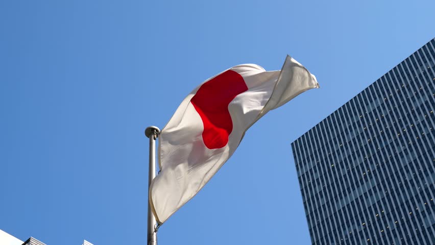 Japan flag waving in the wind – Modern building with blue sky