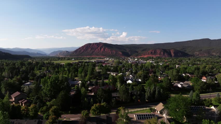 Aerial overview shows Carbondale dense residential blocks mountain ridge rising beyond rolling hills, establishing Colorado overview