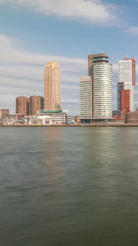 Panorama showing Rotterdam skyline timelapse from Nieuwe Maas River bank to Wilhelminapier and Kop van Zuid. Modern skyscrapers, ship terminal and Erasmus Bridge, waterfront with boats passing by
