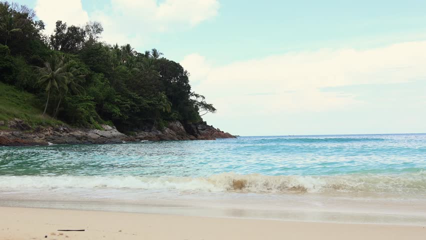 Close up of waves gently breaking onto a sandy beach.