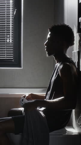 Vertical shot of African American gen Z man with towel around neck gently rubbing face with both hands