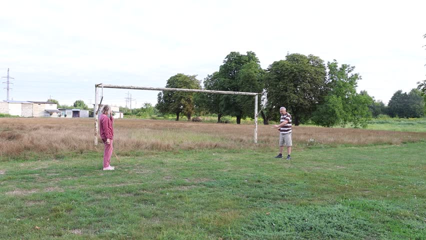 A man and a woman are playing badminton on a sports field, enjoying active outdoor recreation.