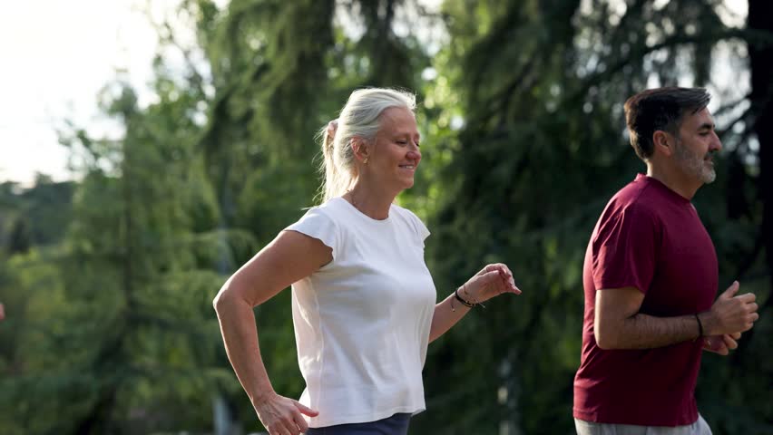 Active senior couple enjoying a healthy lifestyle while jogging together in a park. Middle aged man and woman running outdoors for exercise