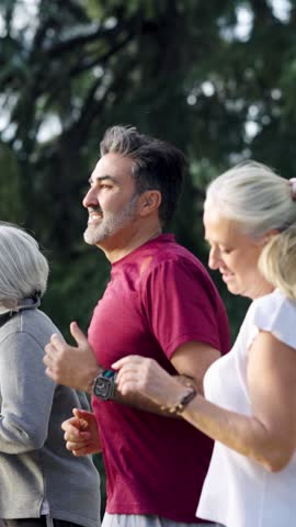 Happy middle aged and senior people jogging together in a park. Active lifestyle and friendship concept for a group of mature friends. Vertical