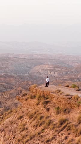 Lone woman standing on a cliff edge, thoughtfully gazing at the breathtaking view of the gorafe desert badlands in granada, spain