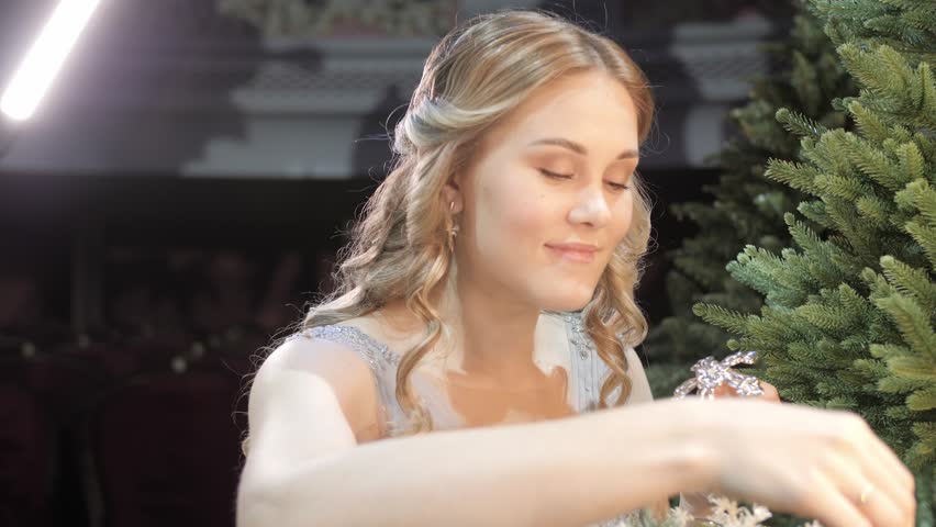 Beautiful young woman decorating a Christmas tree.