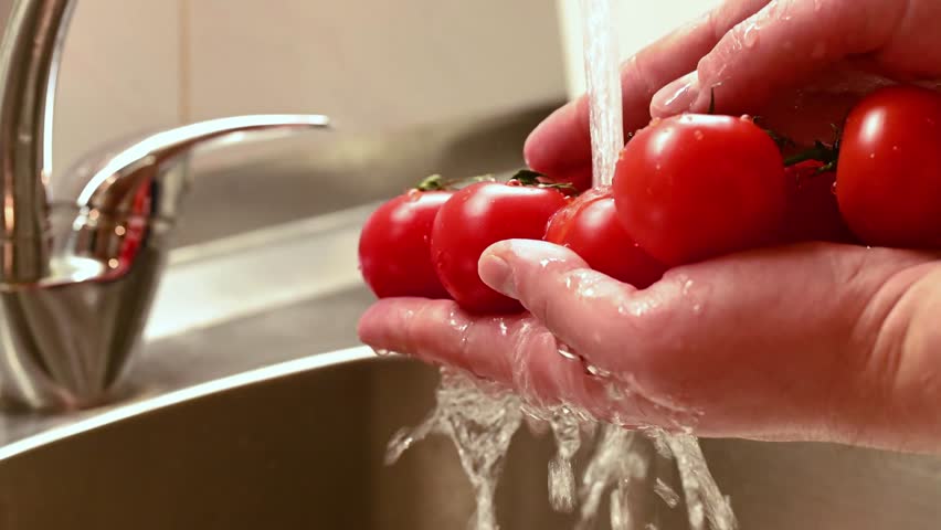 Person man washing tomatoes before cooking vegetarian salad at home