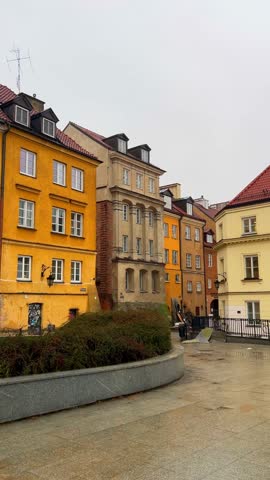 A building with different colors stands in the city of Warsaw, Poland. Grass is nearby and the sky is cloudy. Old Town in Warsaw.