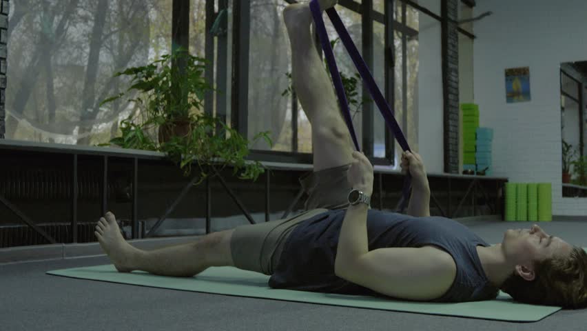 Person using resistance band for leg stretch on mat.