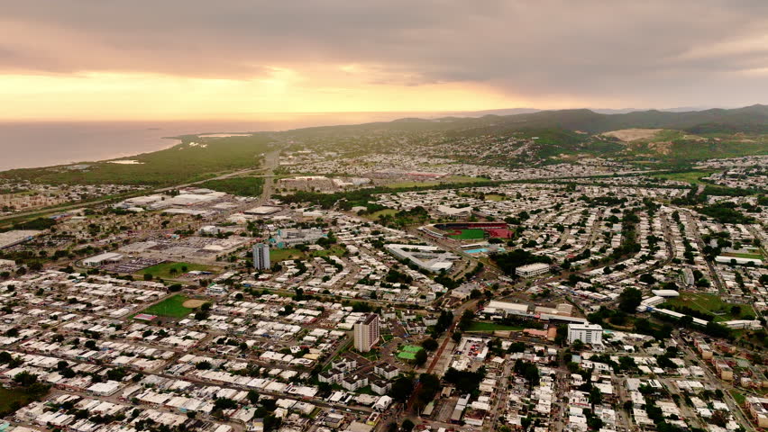 Panoramic aerial top view of the city of Ponce, Puerto Rico, at sunset. City architecture with houses, streets and stadiums on the ocean coast.