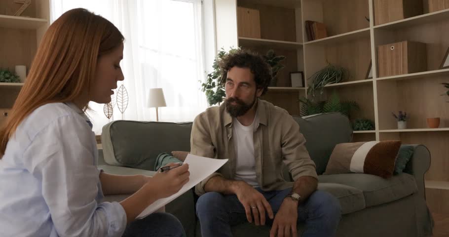 A compassionate female therapist attentively listens as a male client discusses his mental health concerns during a private counseling session. This video highlights professional support and open communication.