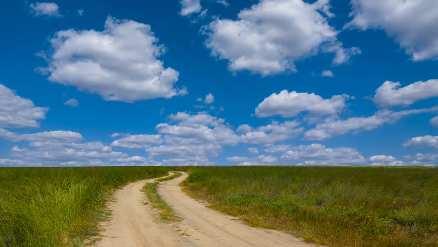 ground road among green prairie under cloudy sky time lapse scene