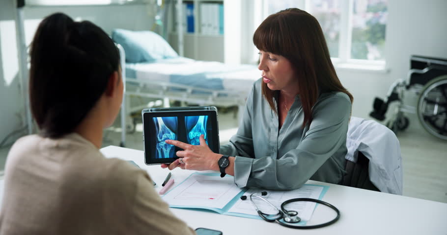Doctor, woman and tablet xray in consultation for bone fracture, explain results and diagnosis. Healthcare, patient and professional with MRI screen in clinic for knee dislocation and treatment plan