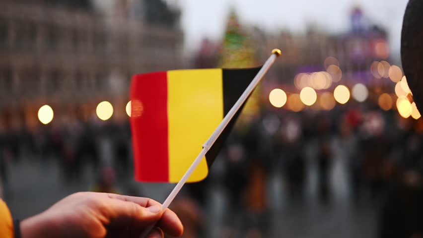 Holding A Belgian Flag In Hand In Front Of A Christmas Tree On The Square