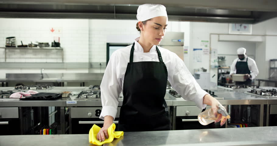 Chef, woman and spray for kitchen counter at restaurant, wipe or hygiene with sanitation process for germs. Person, cloth and bottle with chemical, liquid and cleaning product for bacteria at diner