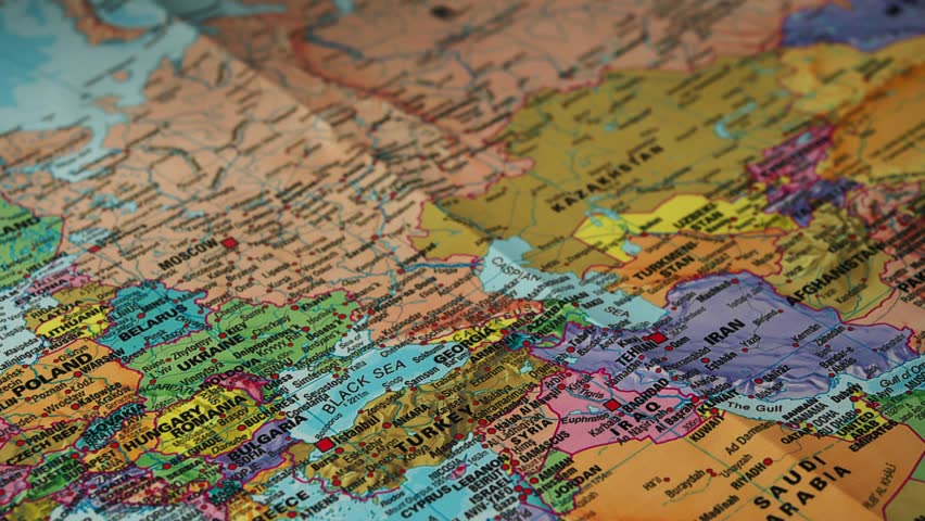 Close up hand carefully placing small Turkey flag on detailed political map of Middle East and Europe, emphasizing concept of geography studies, travel planning, marking important destination.