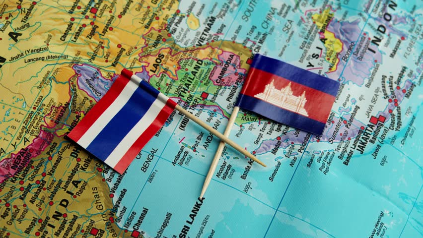 Thailand flag and Cambodia flag lie crossed on political map of Southeast Asia in dramatic close up, symbolizing tense military standoff and fragile border security between neighboring countries.