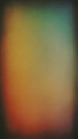 Colorful vintage vignette with soft grainy light transition or blurred rainbow gradients on a textured film surface in a looping video