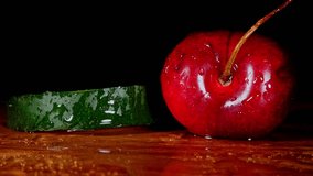 Cinematic slow motion macro of water droplets spraying on fresh green cucumber and ripe red cherry. Detailed organic texture on black background. High quality 4K food stock footage. - Powered by Shutterstock - Get 15% off with code: PIKWIZARD15