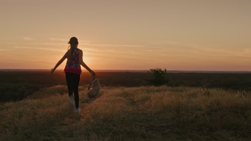 4K silhouette of girl running on hill towards sunset video