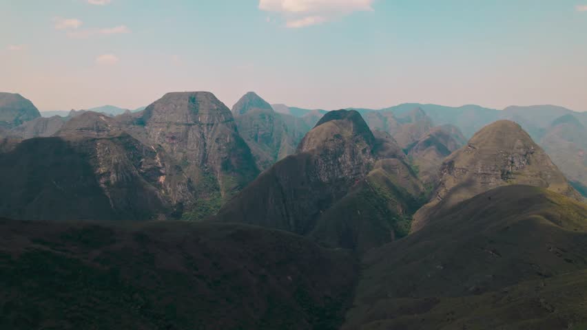 A breathtaking wide aerial or drone shot capturing the vast, rugged, and majestic landscape of the Codo de los Andes mountain range in Bolivia under a clear blue sky, emphasizing natural beauty