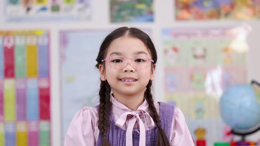 Smiling elementary schoolgirl proudly holds bright yellow number one in colorful classroom setting
