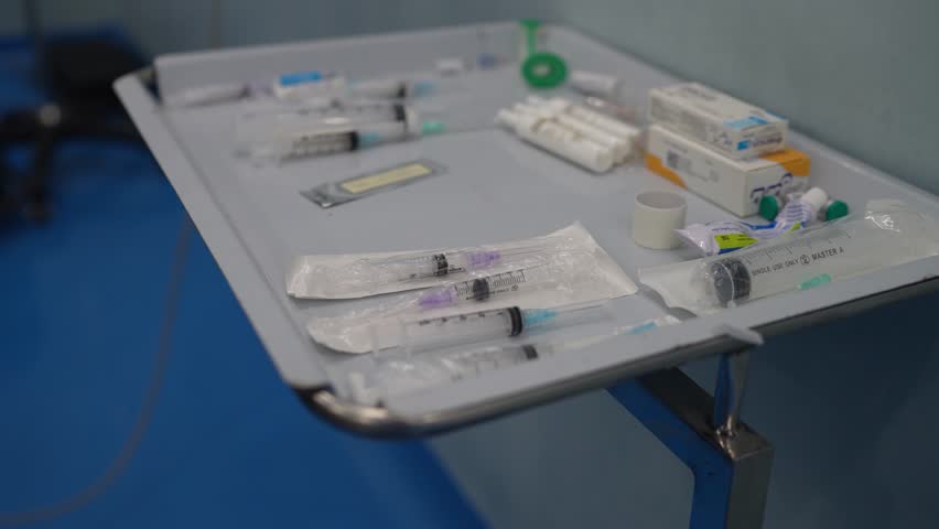 Sterile syringes and medical equipment arranged on tray inside hospital treatment room in Pakistan