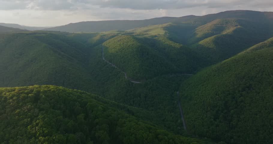 Aerial view of road in lush green mountains in West Virginia, serene landscape