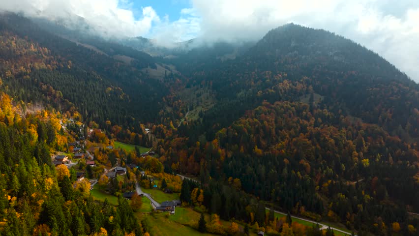 Scenic aerial of Unken village with mountains, conifer forests and rich autumn colors. Heutal, Austria