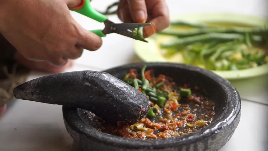 Close up of long bean salad cut with scissors with red chili, authentic Asian food and traditional food preparation methods.