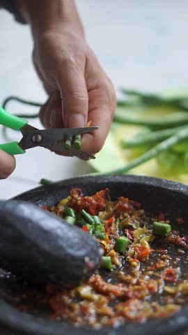 Close up of long bean salad cut with scissors with red chili, authentic Asian food and traditional food preparation methods.