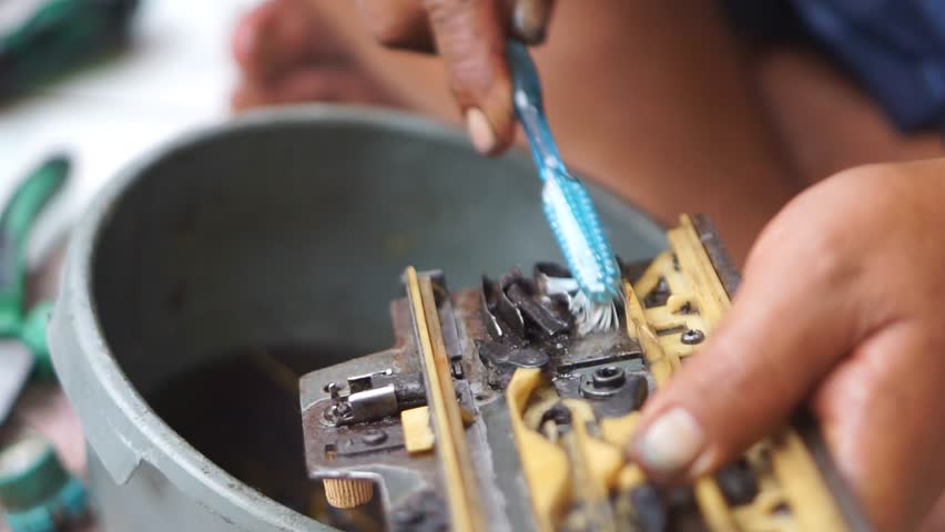 Manual cleaning of machine parts to remove grease and dirt, highlighting precision work and mechanical maintenance	