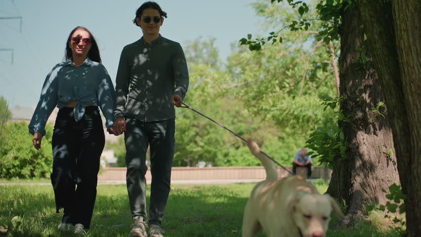 serene couple enjoys shaded park walk, peaceful pair wanders beneath canopy of dappled sunlight shadows, calm and tranquil couple journeys through park under branches casting patterned shadows