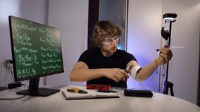 Young engineer calibrates glowing arm implant while coding neural systems in futuristic home lab with digital equations tools and intense focused experimentation for breakthrough - Powered by Shutterstock - Get 15% off with code: PIKWIZARD15