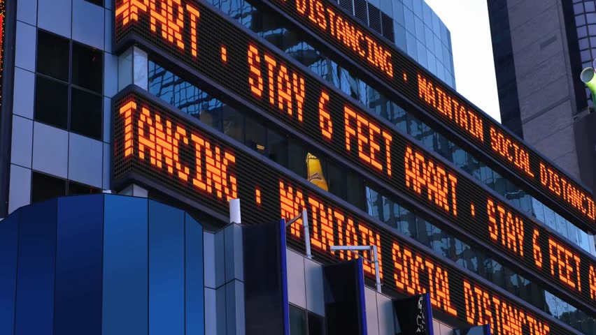 Times Square stock market ticker reminds pedestrians to maintain 6 feet distance, highlighting social distancing during the COVID-19 pandemic.