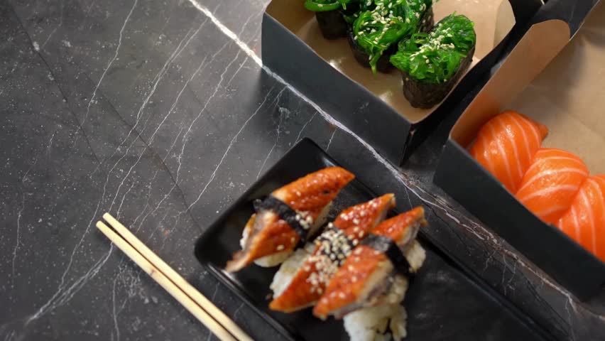 Creation of sushi buffet with salmon and tuna fish, avocado rice and nori sheets, arranged on a plate.	