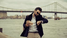 Busy  Businessman Eating Sandwich On The Go While Talking On Mobile Phone And Checking Time On Watch. Professional Executive Having Quick Lunch Break. Multitasking And Time Management. Morning Commute - Powered by Shutterstock - Get 15% off with code: PIKWIZARD15