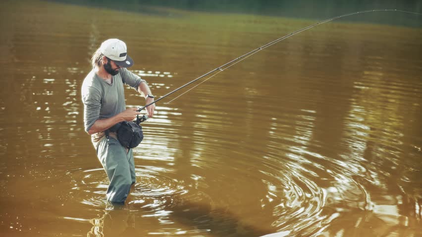 Catching Fish In Fresh Water. Fisher Holding Fishing Rod And Spinning Reel. Sport Fishing Gear Equipment.  Fisherman Angling Fish. Outdoor Hobby And Recreational Activity. Professional Fishing Tackle