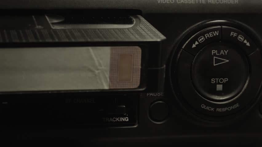 Vhs cassette inserted into vintage vcr player. A retro, video and entertainment concept. Close up, intro shot.