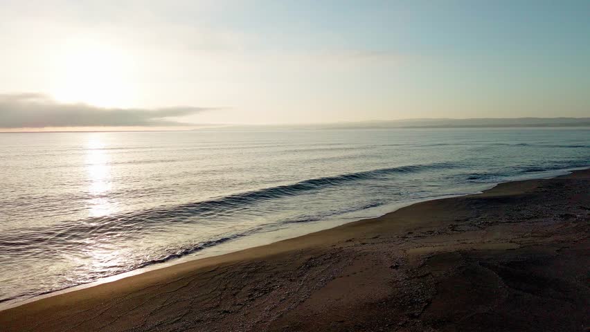 Black Sea and beach nearby against a sky with clouds and a dawn sun
