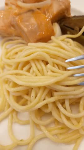 Spaghetti with sliced salmon shows the serving of a gourmet pasta dish featuring spaghetti topped with sliced salmon. The footage captures plating the dish. This video represents fine dining, Italian-inspired cuisine, seafood dishes, and culinary presentation.