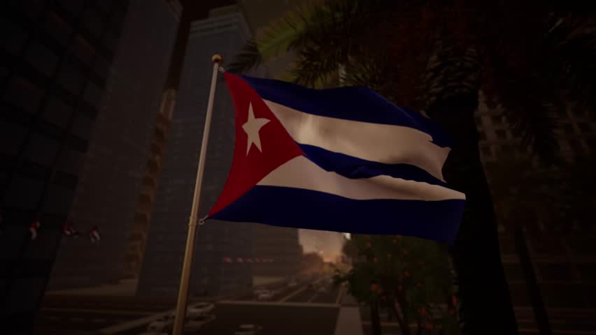 The Cuban national flag waves gently at sunset along a modern city street, illuminated by warm golden light that reflects across surrounding buildings and urban surfaces. The contrast between the blue and white stripes, red triangle, and the warm tones of the sky creates a calm and visually balanced atmosphere. The white star remains clearly visible, reinforcing the flag’s symbolic presence.

Urban elements such as streets, buildings, and light traffic appear in the background without overpowering the composition, keeping the flag as the central focus. The absence of recognizable landmarks allows the image to function as a general representation of Cuba rather than a specific city. Subtle motion in the flag adds realism while preserving a composed and professional tone.

This visual is suitable for editorial use related to international affairs, regional topics, cultural storytelling, or travel features. Its warm lighting and neutral composition provide flexibility for a wide range of informational and media applications.
